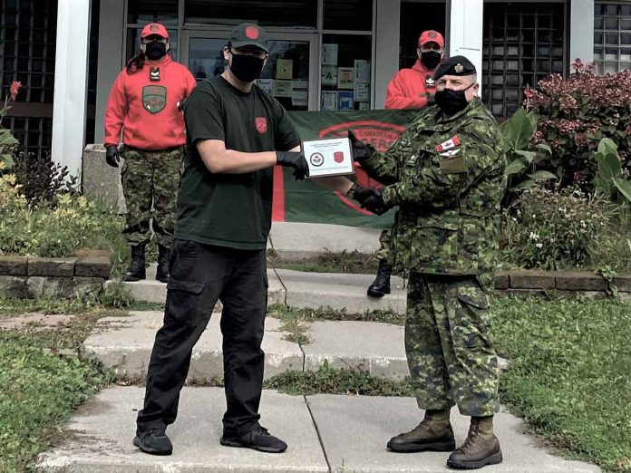Junior Canadian Ranger Michael Baxter, left, receives a cheque for $1,000 to further his education and a plaque from 2nd Lieutenant Jack Teskey of the Canadian Army. Photo credit: Corporal David M. Thompson