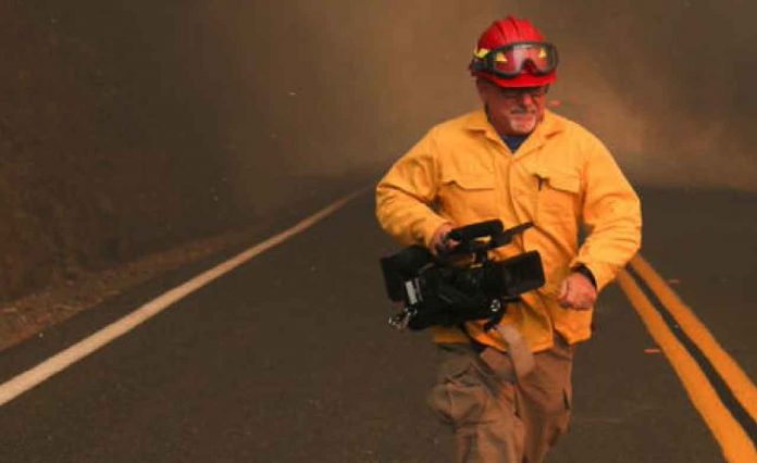 A NBC News journalist takes cover from an approaching LNU Lightning Complex Fire as it engulfs trees and brush in Lake County, California, U.S. August 23, 2020. REUTERS/Adrees Latif