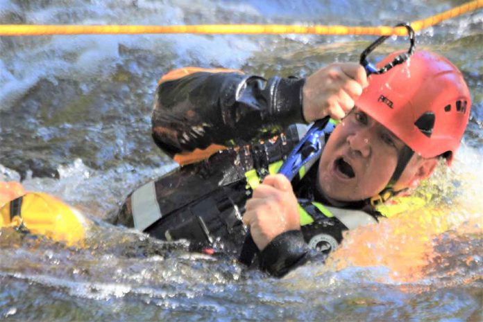 Petty Officer 2nd Class Kevin McCue holds onto a carabiner attached to a rescue rope. credit Master Corporal Christopher Vernon