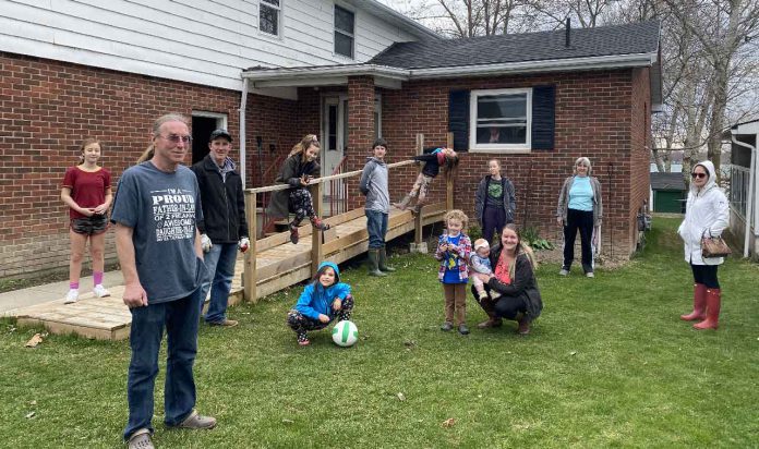 Photo is of my grandmother's 92nd socially distanced birthday. She's in the window. My mother is wearing the teal coloured shirt and black pants to the immediate right of the window. There are four generations of my family represented in this photo, and I am holding the camera - Amanda