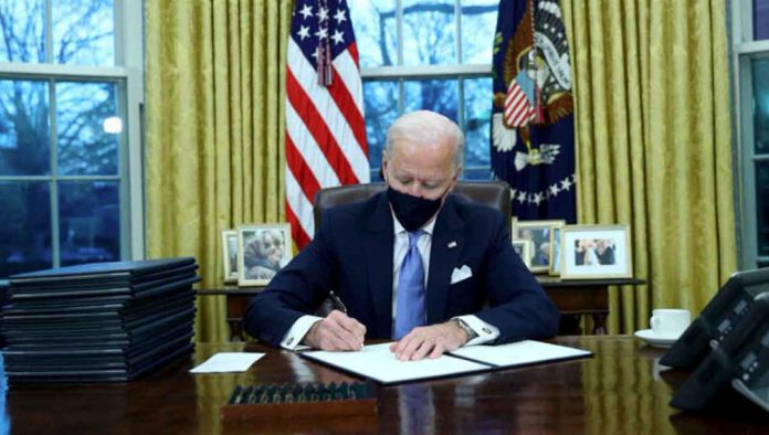 U.S. President Joe Biden signs executive orders in the Oval Office of the White House in Washington, after his inauguration as the 46th President of the United States, U.S., January 20, 2021. REUTERS/Tom Brenner