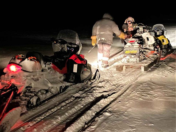 Master Corporal Mike Koostachin and Corporal Maurice Mack load a stranded Peawanuck snowmobiler's broken-down machine onto a toboggan after going to his aid. credit Master Corporal Jason Hunter, Canadian Rangers