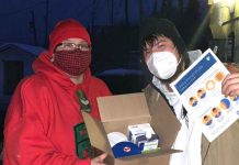 Canadian Rangers Assist in Fort Albany Covid Lockdown Master Corporal Ruby Edwards-Wheesk, left, shows a box containing personal protective equipment to her son Wendell. The boxes are being distributed to every resident of Fort Albany during the crisis. credit Canadian Rangers
