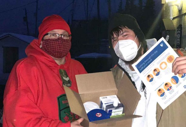 Master Corporal Ruby Edwards-Wheesk, left, shows a box containing personal protective equipment to her son Wendell. The boxes are being distributed to every resident of Fort Albany during the crisis. credit Canadian Rangers