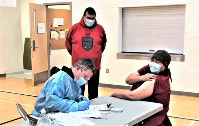 Ranger George Kakekaspan watches Master Corporal Mary Miles get her vaccination in Fort Severn. Credit Master Corporal Angus Miles, Canadian Rangers