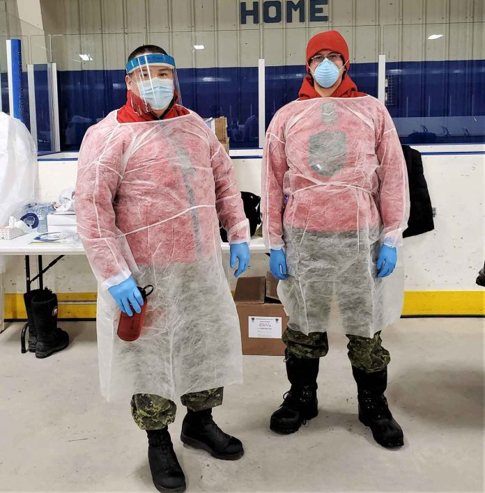 Sergeant Byron Corston and Ranger Nathaniel Keesic wear protective gowns while assisting a medical team delivering COVID-19 vaccinations in Moose Factory. credit Canadian Rangers