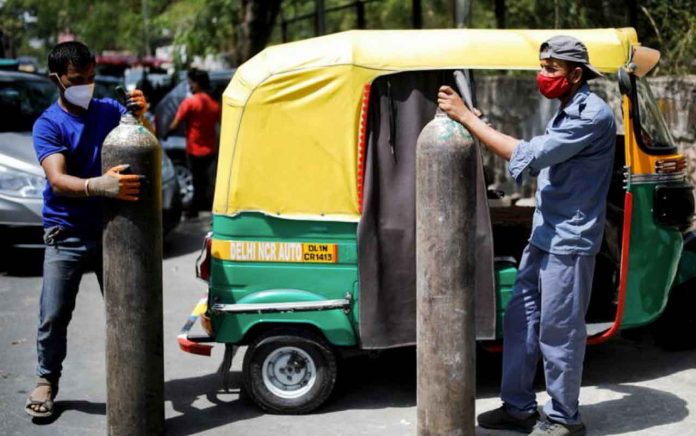 FILE PHOTO: Rickshaw drivers hold oxygen cylinders outside a private refilling station, amid the coronavirus disease (COVID-19) outbreak, in New Delhi, India, April 19, 2021. REUTERS/Adnan Abidi/File Photo