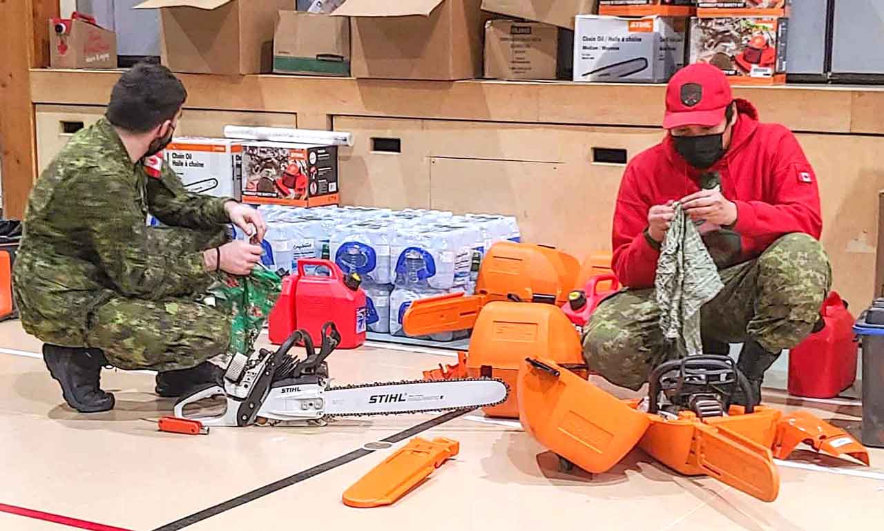 A soldier and a Canadian Ranger organize emergency supplies for distribution in Deer Lake First Nation credit Canadian Rangers