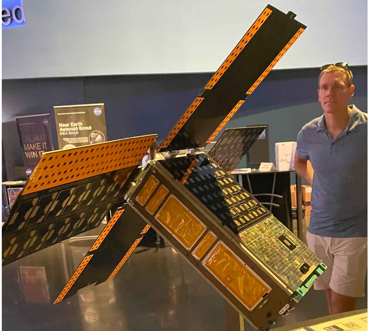 Dr. Chris Thome beside a 6U CubeSat spaceship at NASA Kennedy Space Center. 