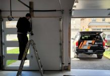 Insider’s Perspective: The Life of a Garage Door Repair Technician A handyman fixing a roll-up garage door while standing on a ladder
