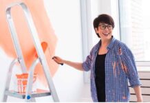 Exterior Painting Tips for Seattle Homes Battling Moisture and Mold Smiling woman paints wall with roller, capturing the DIY spirit—and the potential mess—of painting your room without a pro.