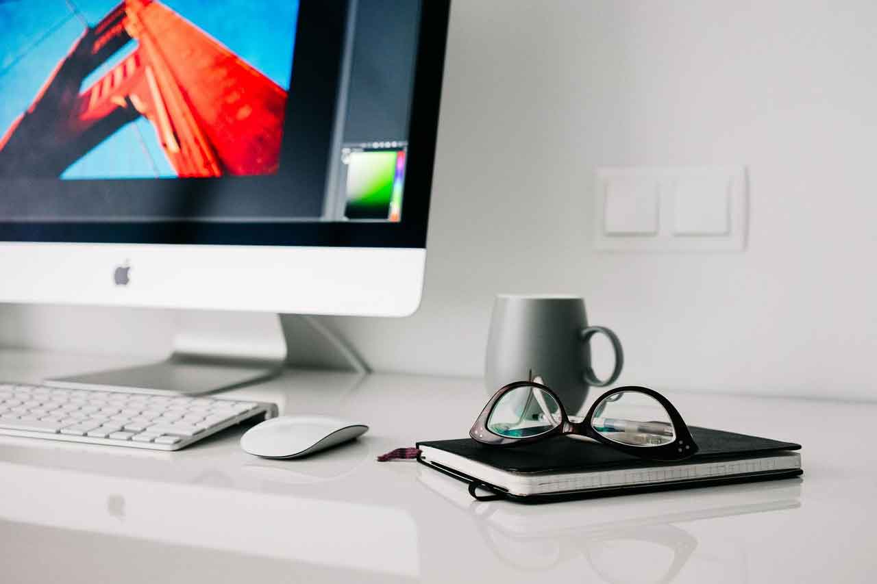 Apple iMac and mouse with book and glasses