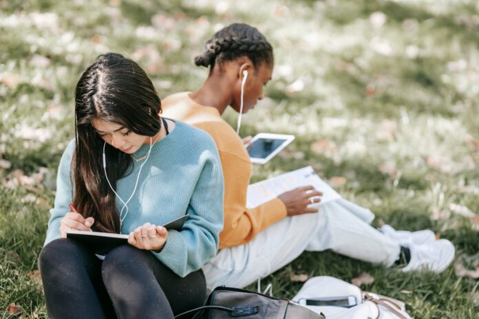 Photo by Charlotte May: https://www.pexels.com/photo/multiracial-young-women-using-tablet-and-writing-in-notebook-5965895/