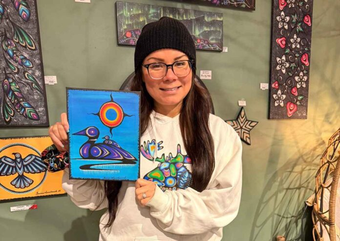 Artist Jessica Mamakeesick posing with her painting, Mother Loon. Artist Jessica Mamakeesick posing with her painting, Mother Loon.